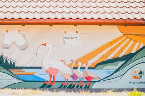 a mural of three birds on the side of a building at RiW Małe Swory - Domek pływający Houseboat in Małe Swornegacie