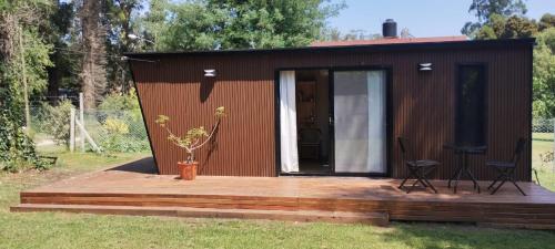 a small shed with a wooden deck and a chair at Tiny House del Bosque in Mar del Plata