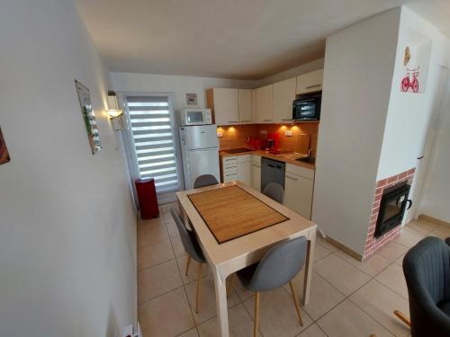 una pequeña cocina con mesa de madera y sillas en La Villa Bleue avec piscine, en Bretignolles-sur-Mer