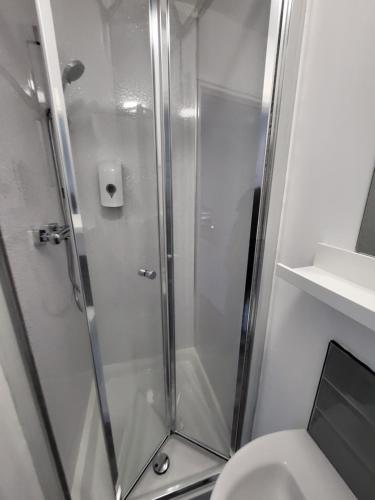 a shower with a glass door next to a toilet at Stay Sleep Rest - Alfreton Road in Nottingham