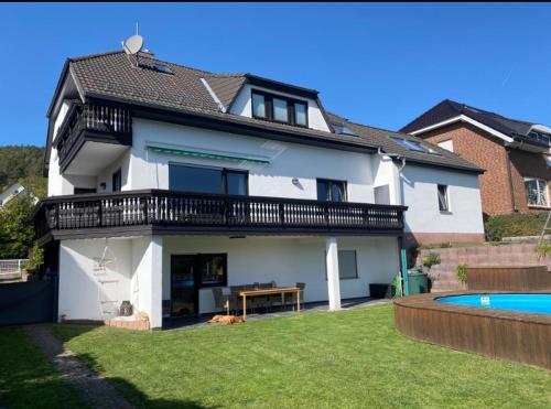 Cette maison blanche dispose d'un balcon et d'une piscine. dans l'établissement Ferienwohnung am Tor zum Thüringer Wald, à Plaue