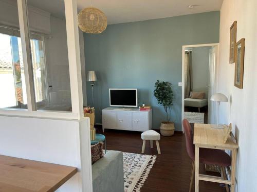 ein Wohnzimmer mit einem TV und einem Schreibtisch mit einem Tisch in der Unterkunft La casa magique, bulle enchantée, 100m de la plage in Andernos-les-Bains