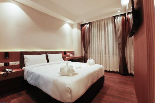a hotel room with a large bed with white sheets at Lakhey Hotel in Kathmandu