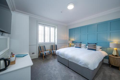 a bedroom with a large bed with blue walls at The Golden Lion Hotel in Hunstanton
