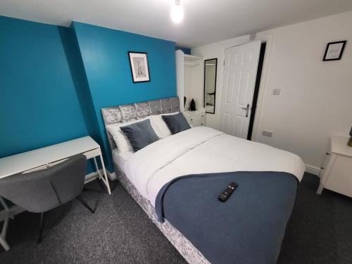 1 dormitorio con 1 cama con pared azul y escritorio en Stay Sleep Rest - Alfreton Road en Nottingham