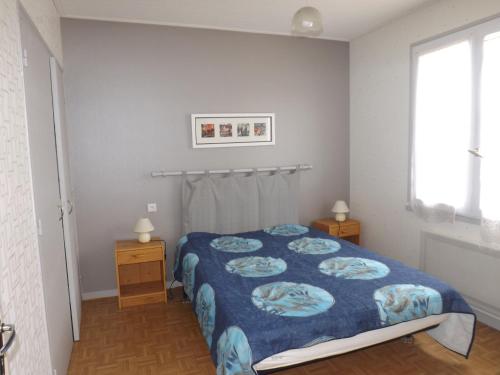 a bedroom with a bed with a blue comforter at Le Boisvinet in Saint-Gilles-Croix-de-Vie