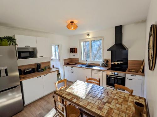 a kitchen with a table and a kitchen with white cabinets at Le Monné - Gîte tout confort in Campan