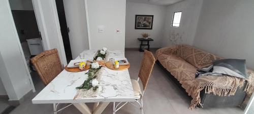 einen weißen Tisch mit Stühlen und ein Sofa im Wohnzimmer in der Unterkunft Casinha da paz in Jaú