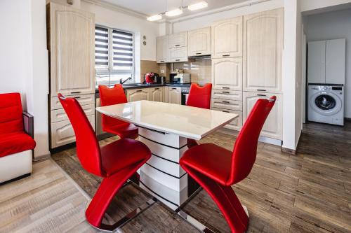 a kitchen with red chairs and a white table at Leon's home in Şelimbăr