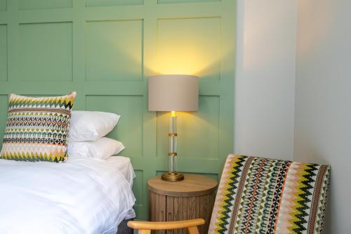 a bedroom with a bed and a lamp and a chair at The Golden Lion Hotel in Hunstanton