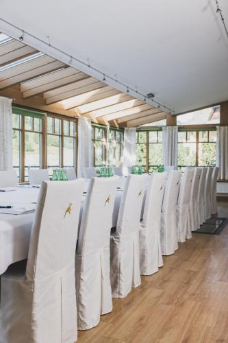 a row of white chairs in a room with windows at Seehotel Jägerwirt in Turracher Hohe