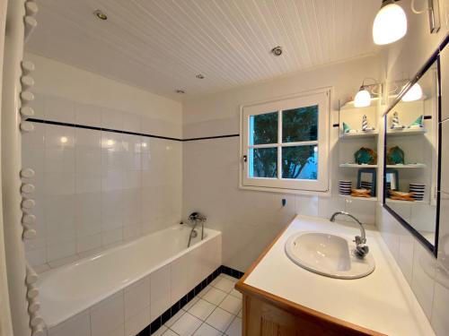 La salle de bains blanche est pourvue d'un lavabo, d'une baignoire et d'une baignoire. dans l'établissement Le brisou 400 m de la plage quartier Boisvinet, à Saint-Gilles-Croix-de-Vie