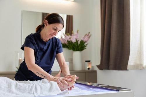 a woman is giving a patient a foot massage at CasaMartini Bed & Breakfast in Fonte