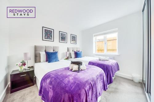 2 camas en una habitación blanca con mantas moradas en Modern Serviced Apartments For Contractors & Families With FREE Parking, WiFi & Netflix By REDWOOD STAYS en Basingstoke