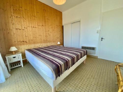 - une chambre avec un lit et un mur en bois dans l'établissement La Sauvageonne, à Saint-Gilles-Croix-de-Vie