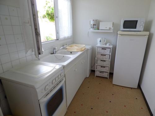 une cuisine blanche avec un évier et une cuisinière dans l'établissement L'Atlantique, à Saint-Gilles-Croix-de-Vie