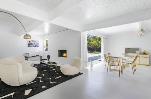 sala de estar con paredes blancas, mesa y sillas en Former Steve McQueen’s home en Palm Springs
