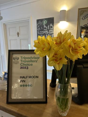 a vase filled with yellow flowers next to a sign at The Half Moon Inn Rushall IP21 4QD in Pulham Saint Mary the Virgin