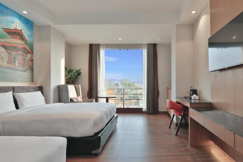 a hotel room with a bed and a large window at Lakhey Hotel in Kathmandu