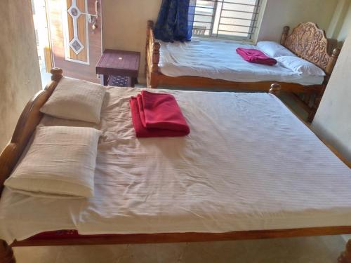 Gopal beach house في كاروار: سريرين في غرفة عليها منشفة حمراء