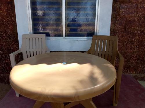 een tafel en twee stoelen voor een raam bij Gopal beach house in Kārwār