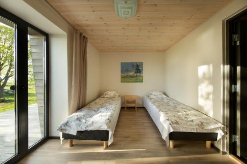 two beds in a room with large windows at Pikla Linnumaja in Piirumi