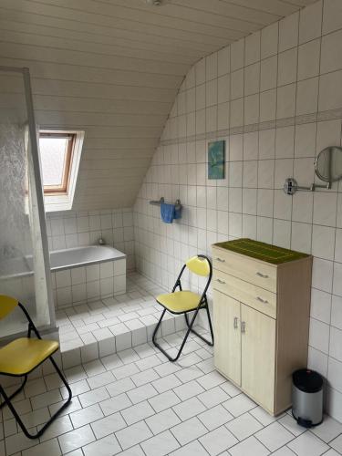a bathroom with two chairs and a sink and a tub at Ferienwohnung Gut-Wattberg in Hofgeismar