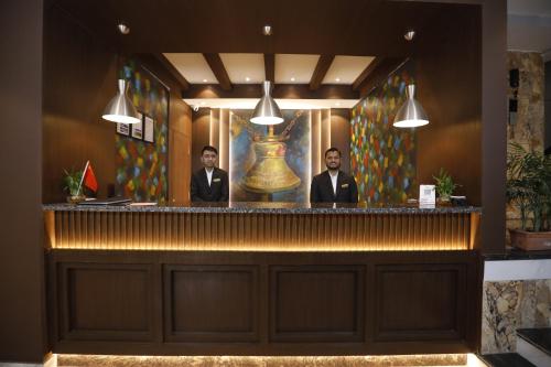 two men standing behind a bar in a room at Lakhey Hotel in Kathmandu