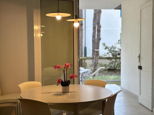 a dining room table with a vase of flowers on it at Villa Giorgio 1 relax in pineta in Bibione