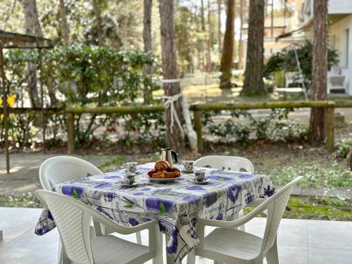 a table with chairs and a plate of food on it at Villa Giorgio 1 relax in pineta in Bibione