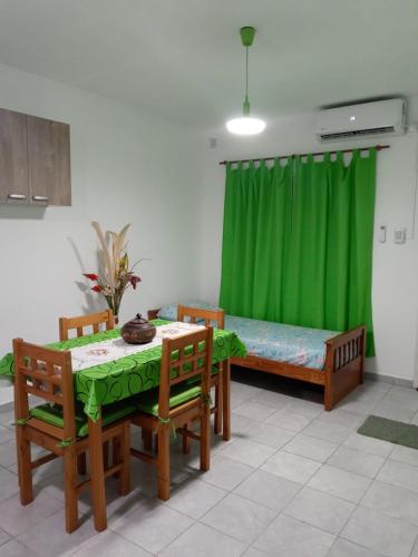 um quarto com uma mesa e cadeiras e uma cortina verde em Miró departamento con cochera em Villa María