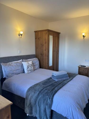 a bedroom with two beds and a wooden cabinet at The Half Moon Inn Rushall IP21 4QD in Pulham Saint Mary the Virgin