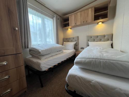 a bedroom with two beds and a window at Lapwing 60, Scratby - California Cliffs, Parkdean, sleeps 6, bed linen and towels included, no pets in Great Yarmouth