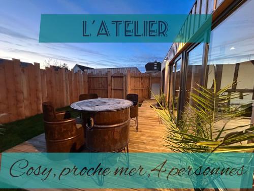 a patio with a table and a fence at L'atelier de la clef des Paons in Luc-sur-Mer
