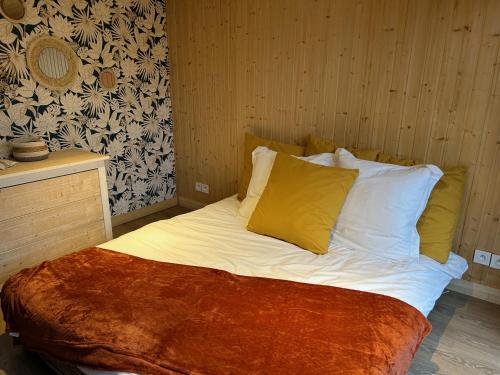 a bed with white sheets and yellow pillows in a room at L'atelier de la clef des Paons in Luc-sur-Mer