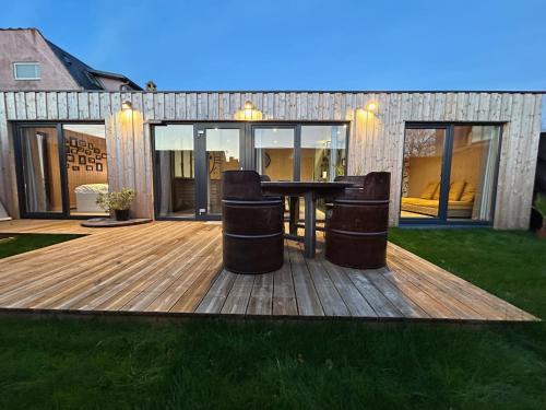 a deck with a table and two trash cans at L'atelier de la clef des Paons in Luc-sur-Mer