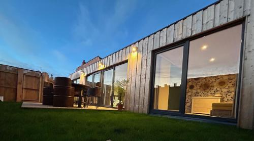 a building with large windows and green grass at L'atelier de la clef des Paons in Luc-sur-Mer