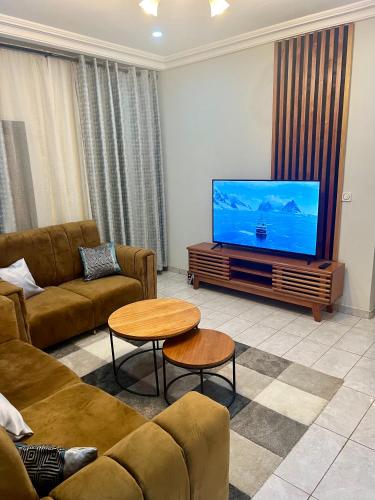 a living room with a couch and a flat screen tv at Hacienda Residence - Solar Energized in Yaoundé