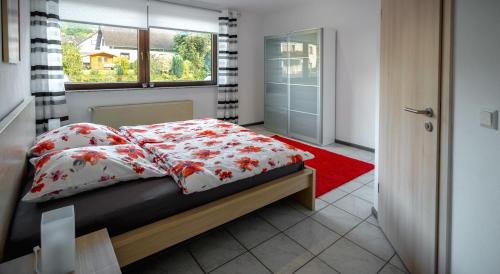 sypialnia z łóżkiem, oknem i czerwonym dywanem w obiekcie Moseltraum w mieście Bruttig-Fankel