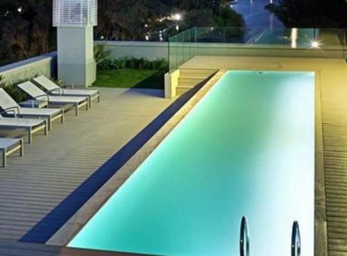 a swimming pool with chairs on a deck at night at Hermoso depto con amenities en Belgrano in Buenos Aires