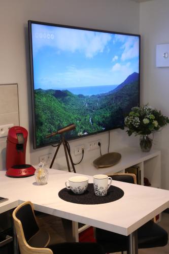 a large screen tv on a table with two cups at Bulles Emotions in Arbois