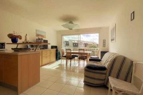a kitchen and living room with a couch and a table at Appartement Anaïs au calme à quelques pas de la mer avec wifi in Merlimont