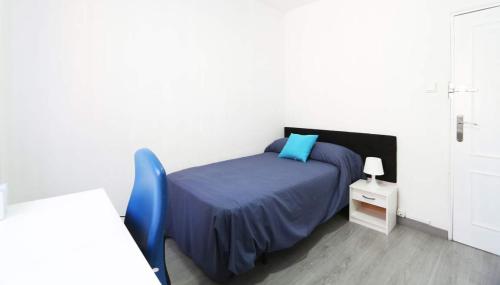 ein Schlafzimmer mit einem Bett und einem blauen Stuhl in der Unterkunft CasaGoa in Madrid