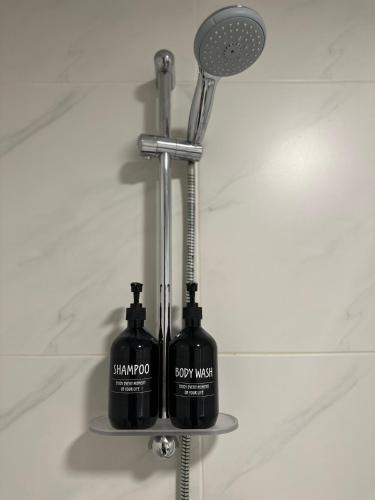 two bottles of shampoo and a shower head in a bathroom at Elegant 3-Bed room Sea-View in Muscat