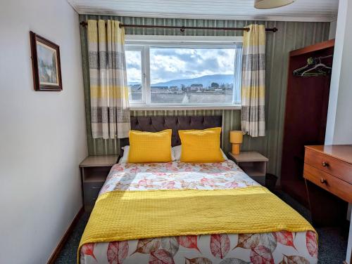 a bedroom with a bed with yellow pillows and a window at Fairy Bridge Lodge in Bundoran