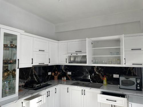 a white kitchen with white cabinets and a microwave at Villa71 in Pogradec