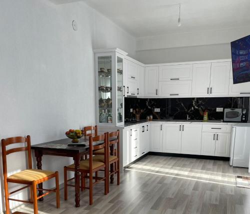 een keuken met witte kasten en een tafel en stoelen bij Villa71 in Pogradec