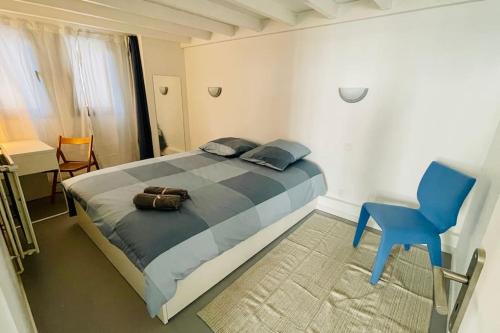 une chambre avec un grand lit et une chaise bleue dans l'établissement Maison/loft Paris 14eme, à Paris