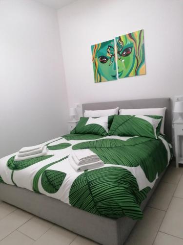 1 dormitorio con 1 cama con una pintura en la pared en Casa d'Arte 1, en Gravina di Catania