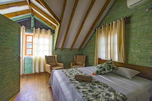 a bedroom with a bed and two chairs and a window at Ambiance Villa in La Digue